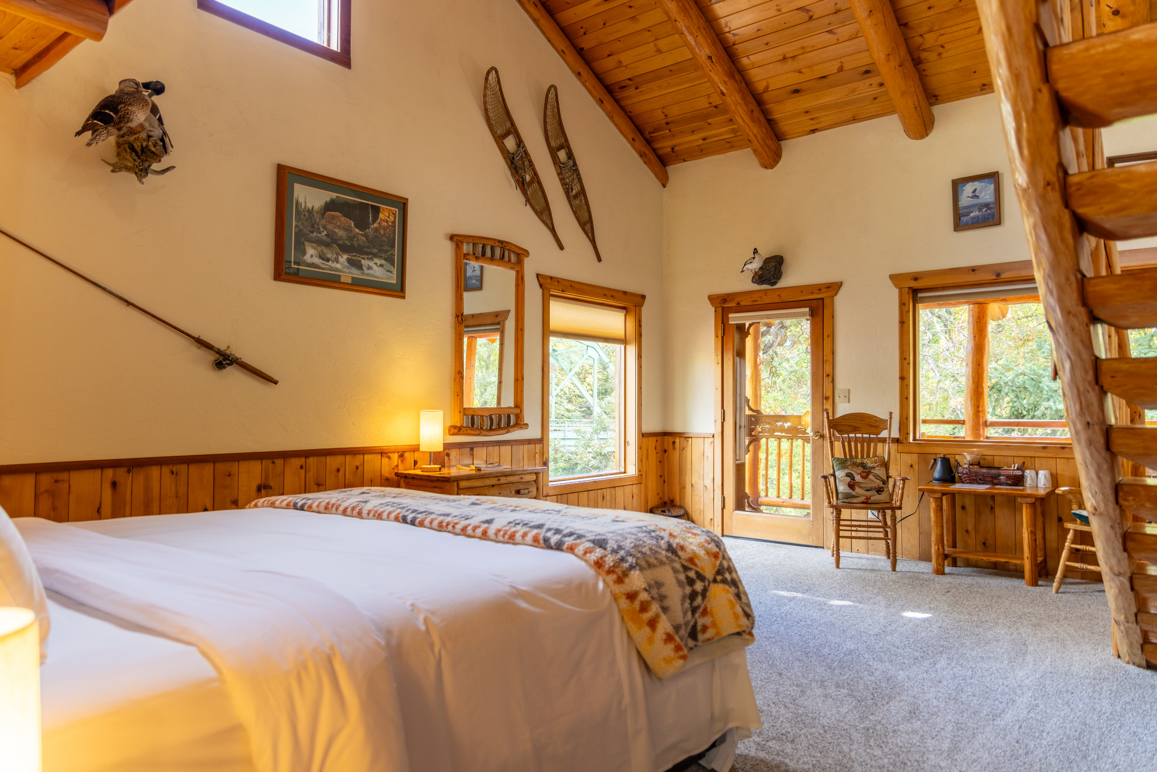 Vaulted log ceiling lodge room with king bed and river views