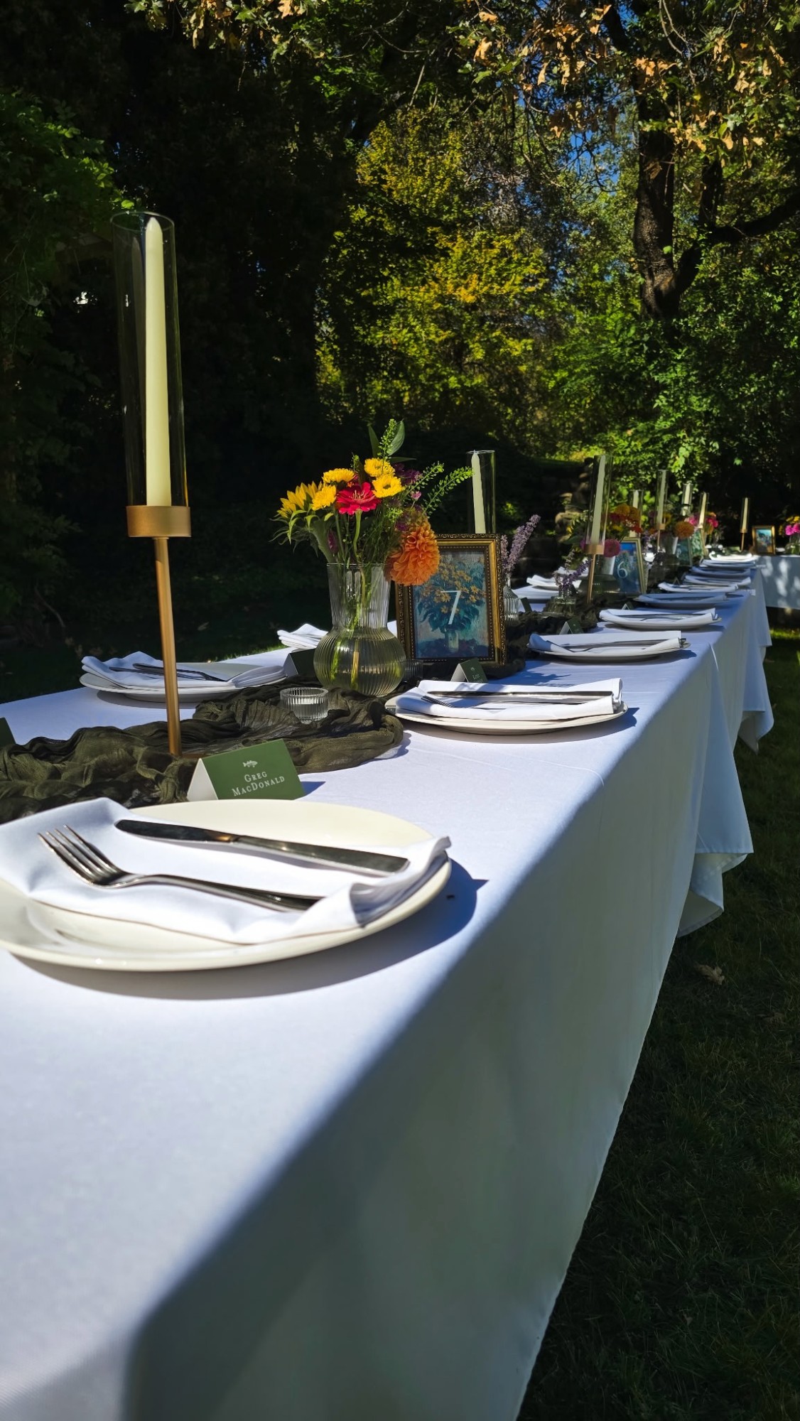 Long riverside wedding reception table with floral centerpieces and gold candlesticks
